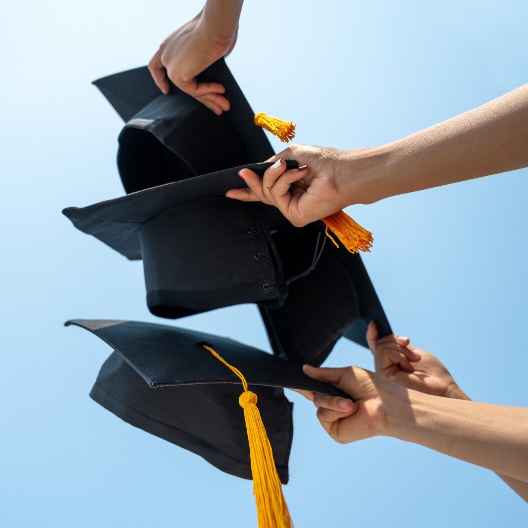 hands throwing mortor boards (graduation hats) into the air